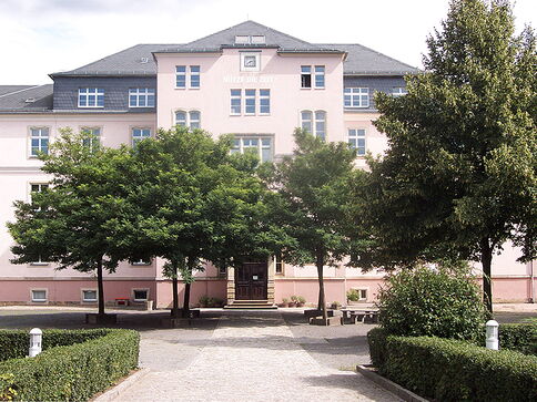 rosafarbenes Schulgebäude mit Bäumen auf dem Schulhof