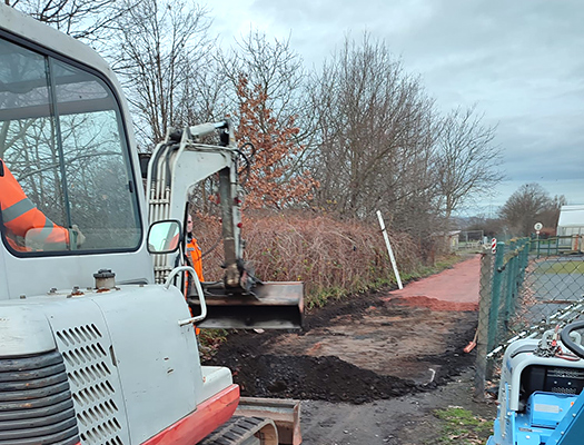 Reparatur des Grenzweges - Bagger verteilt Mineralgemisch
