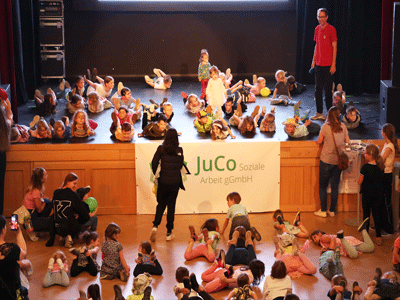 viele Kinder liegen vor und auf der Bühne