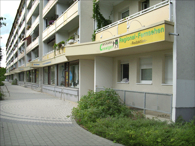 große Häuserfront mit Werbetafel vom Coswiger Infokanal K3