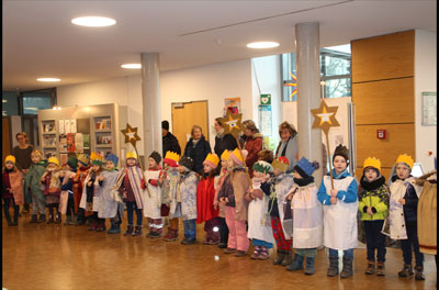 große Kindergruppe mit gelben Kronen auf den Köpfen stehen im Foyer des Rathauses