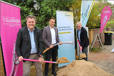 Drei Herren stehen an einem Sandhaufen symbolisch für den Spatenstich zum Glasfaserausbau.