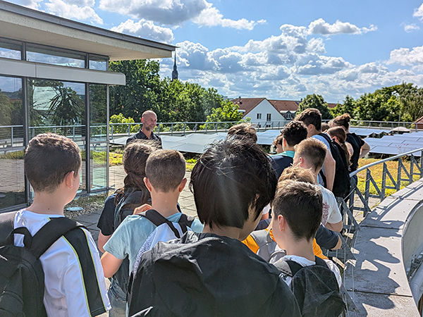 Schülergruppe steht vor Photovoltaikanlage auf dem Rathausdach